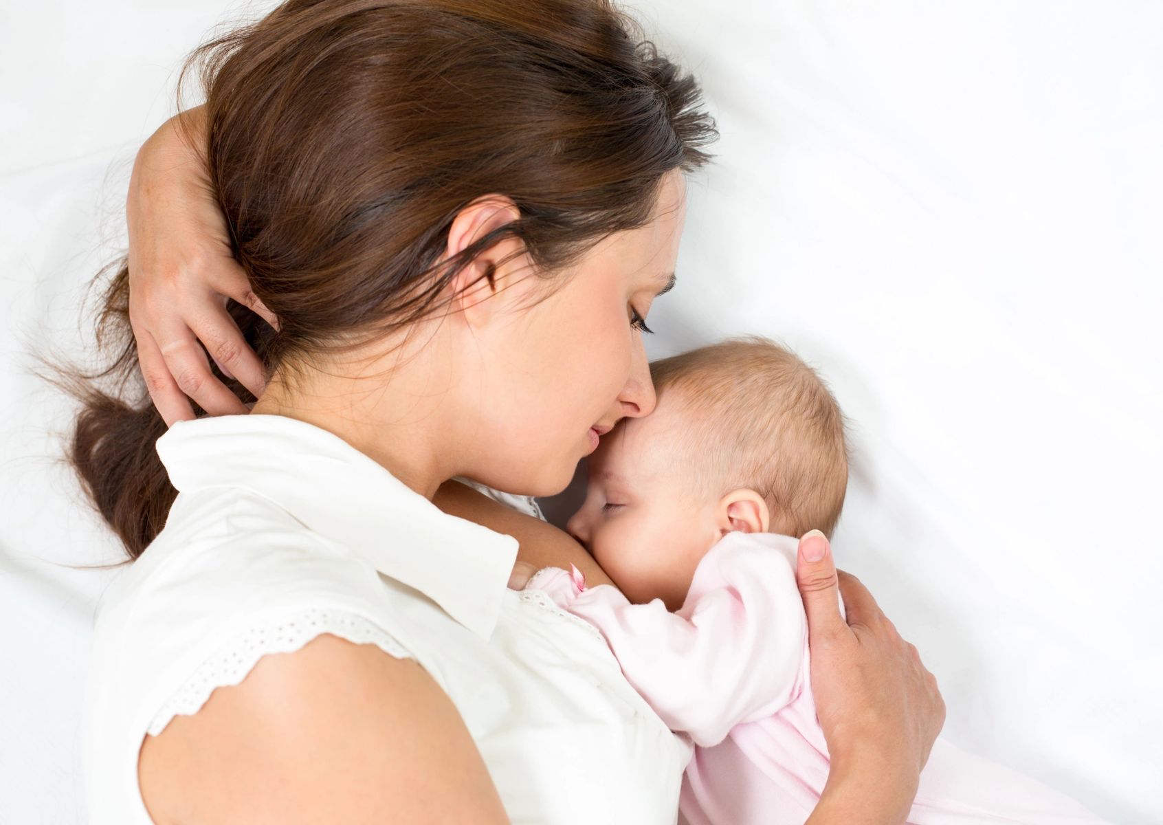 A parent feeding her sleeping baby.
